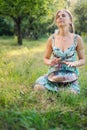 Woman sitting near in the park and playing on happy drum
