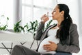 Woman sitting in office chair and drinking water Royalty Free Stock Photo