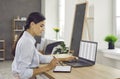 Woman sitting at office desk, working on laptop and tablet computers and using stylus pen Royalty Free Stock Photo