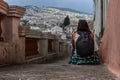 A woman sitting on old stairs of the old town of Quito, Ecuador. She is with her back turned and a beautiful mount landscape of