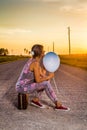 Woman sitting on an old suitcase in the middle of a rural road Royalty Free Stock Photo