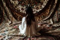 woman sitting on an ornate, arabianpatterned bedspread