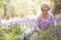 Woman sitting outdoors with flowers smiling Royalty Free Stock Photo