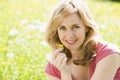 Woman sitting outdoors holding flower smiling Royalty Free Stock Photo