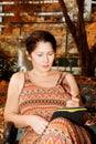 Woman sitting on a park bench and reading e-book Royalty Free Stock Photo