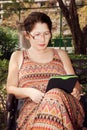 Woman sitting on a park bench and reading e-book Royalty Free Stock Photo