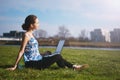 Woman sitting in park on the green grass with laptop. Computer screen mockup. Student studying outdoors. Copy space for text. Beau Royalty Free Stock Photo