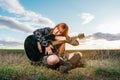 Woman sitting in a park hugging her black guitar under cloudy sky Royalty Free Stock Photo