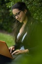 A woman sitting in a park and working with her laptop. Royalty Free Stock Photo