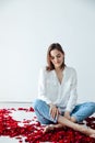 beautiful woman sitting in the petals of a red rose Royalty Free Stock Photo