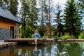 Woman, sitting on a pier,near private lake, relaxing, enjoying cup of morning coffee on summer vacation in mountains. Royalty Free Stock Photo