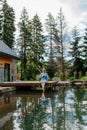 Woman, sitting on a pier,near private lake, relaxing, enjoying cup of morning coffee on summer vacation in mountains. Royalty Free Stock Photo