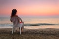 Woman sitting on plastic chair on beach