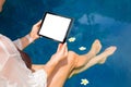 Woman sitting by the pool and using tablet computer. Horizontal screen orientation. Royalty Free Stock Photo