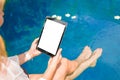 Woman sitting by the pool and using tablet computer. Vertical screen orientation. Royalty Free Stock Photo