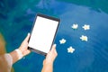 Woman sitting by the pool and using tablet computer. Vertical white screen Royalty Free Stock Photo