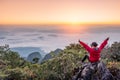 Woman sitting and raise hands up on hill with fog in sunrise at wildlife sanctuary Royalty Free Stock Photo