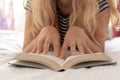 Woman sitting relaxed on the bead reading a book