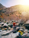 The woman sitting on the rock mountain.