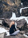 The woman sitting on the rock mountain.