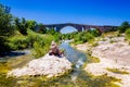 Woman sitting on the rock and painting roman bridge Pont Julien in Provence