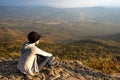 A woman sitting on rocky mountain looking out at scenic natural view and beautiful blue sky Royalty Free Stock Photo