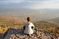 A woman sitting on rocky mountain looking out at scenic natural view and beautiful blue sky