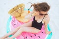 Woman sitting on round watermelon towel and adjusting sunglasses