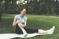 A woman is sitting on a rug for yoga in the park. She was engaged and traumatized her leg.