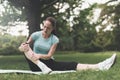 A woman is sitting on a rug for yoga in the park. She was engaged and traumatized her leg.