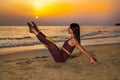 Beautiful woman doing pilates exercise with ball on the beach at sunset.