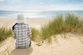 Woman sitting in sand dunes looking at sea Royalty Free Stock Photo