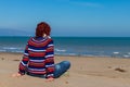 Woman sitting on the sand looking at the sea