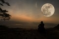 Woman sitting serenely of the cliff and looking at the valley and mountains with moon Royalty Free Stock Photo