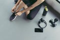 Woman sitting shoelaces with protein shake and dumbbell at fitness gym Royalty Free Stock Photo