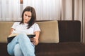 Woman Sitting On Sofa And Attentively Reading Bible. Religion Concept Royalty Free Stock Photo