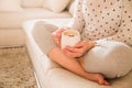 Woman sitting on the sofa and drinking coffee at home. Closeup of woman hands holding cup of coffee with nice star