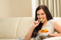 Woman sitting on sofa eating mixed salad Royalty Free Stock Photo