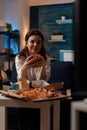 Woman sitting on sofa eating tasty delicious burger watching television enjoying comedy show Royalty Free Stock Photo