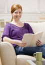 Woman sitting on sofa enjoying reading book