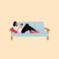 Woman sitting on sofa holds smartphone in her hand. Casual lady and browsing social media on mobile device. Girl on Royalty Free Stock Photo