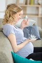woman sitting on sofa at home holding baby shoes Royalty Free Stock Photo