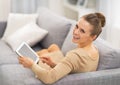 Woman sitting on sofa and using tablet pc Royalty Free Stock Photo