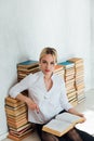 woman sitting on stacks of educational books in library Royalty Free Stock Photo