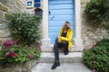 A woman is sitting on the steps in front of the door