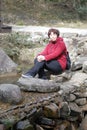 Woman sitting on the stone by the river, adobe rgb Royalty Free Stock Photo