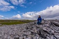 Woman sitting on the stones of the rocky beach of Inis Oirr Island