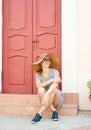 Woman sitting on strairs next to the bright red door Royalty Free Stock Photo