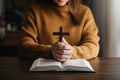 Woman sitting and studying the scriptures.The  wooden cross in the hands. Christian education concepts The Holy Scriptures open Royalty Free Stock Photo