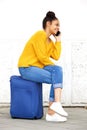Woman sitting on suitcase and talking on cellphone Royalty Free Stock Photo